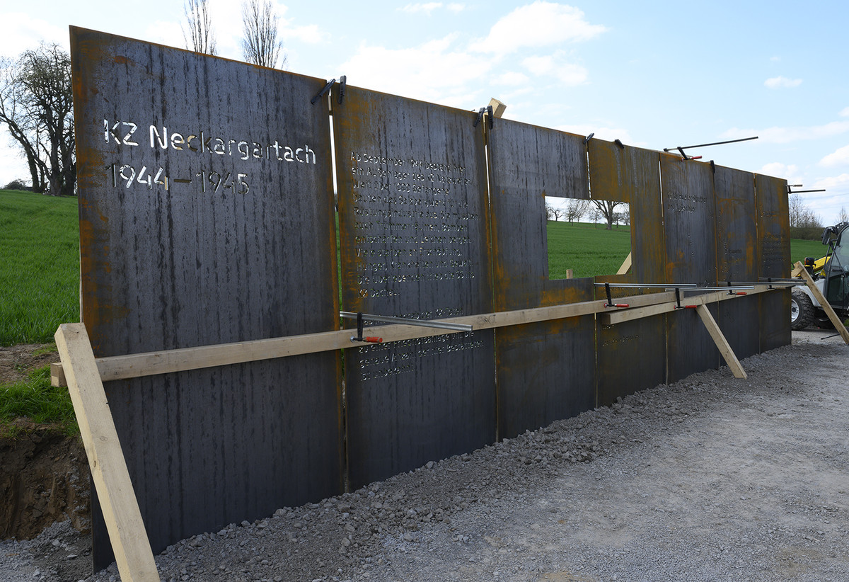 eine Wand aus 7 Cortenstahl-Elementen steht im Freien am Rande eines Ackers neben der KZ-Friedhofsanlage. Die Wand ist 10,5 mlang und 2,5 m hoch und enthält Inschriften über das KZ Neckargartach und eine Karte mit dem KZ-Komplex Natzweiler.